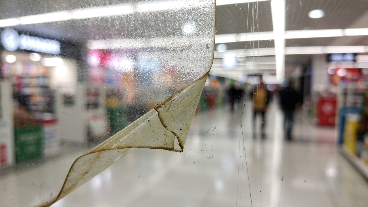 Peeling vinyl decal on commercial storefront glass surface