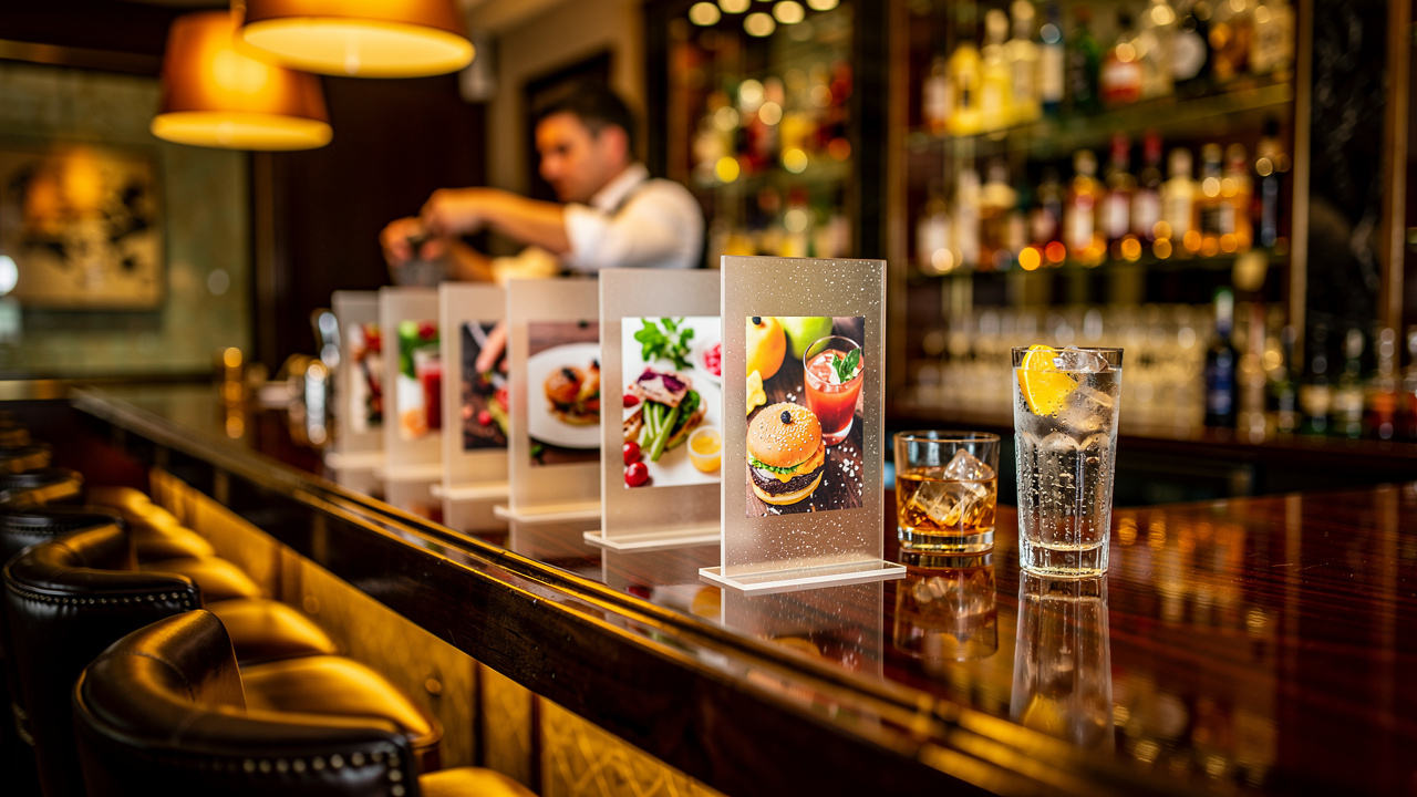 UV-printed acrylic menu holders displayed on a luxury hotel bar counter